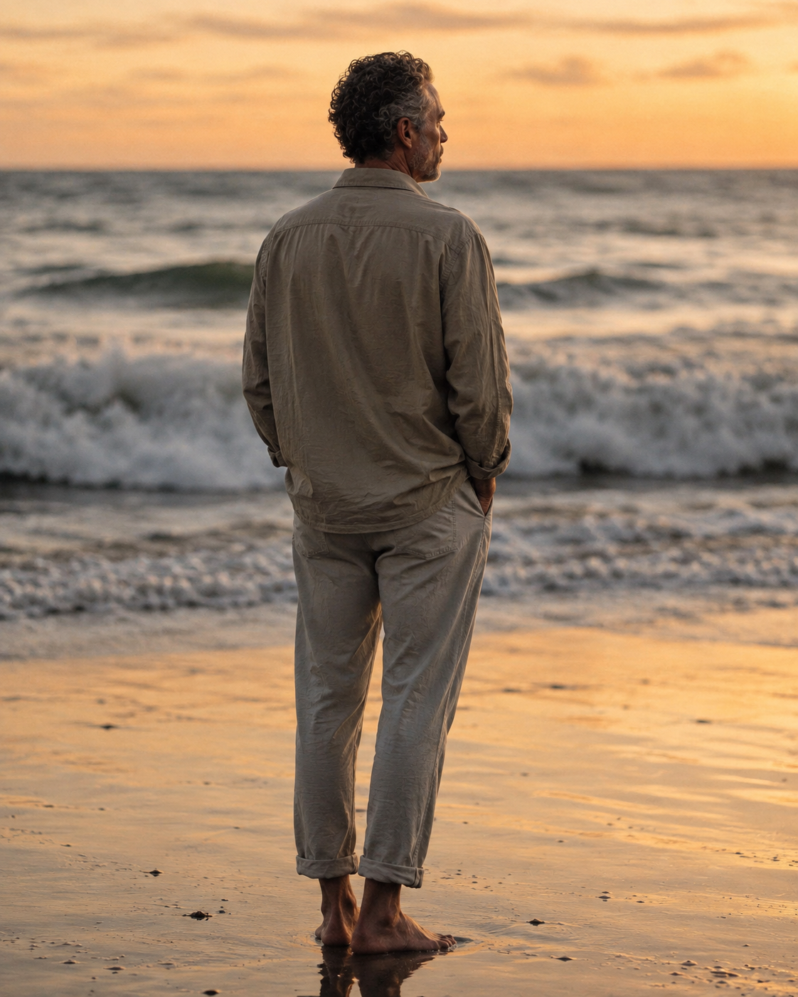 Man standing at the shoreline at sunset